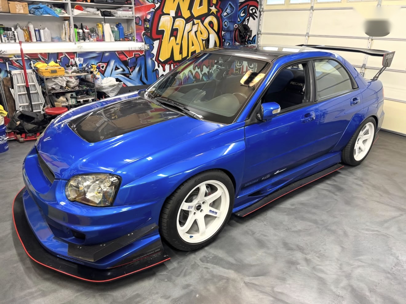 A blue Subaru WRX with a chrome delete and tinted windows